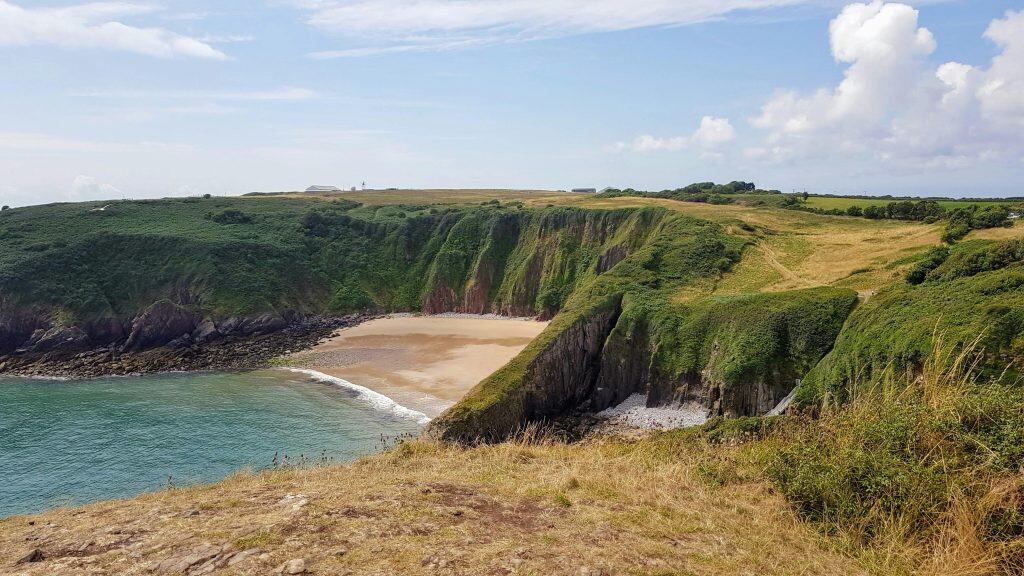 Peaceful UK beach cove framed by cliffs and clear skies-a quiet family-friendly coastal escape
