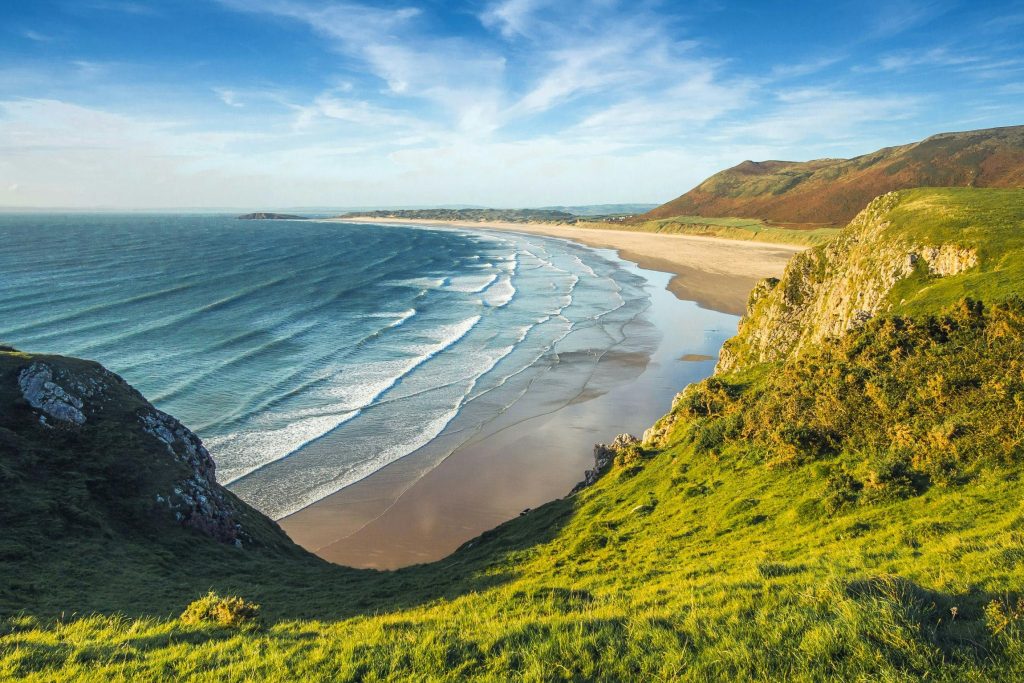 Secluded sandy UK beach with rolling waves and grassy cliffs — ideal for peaceful family getaways.