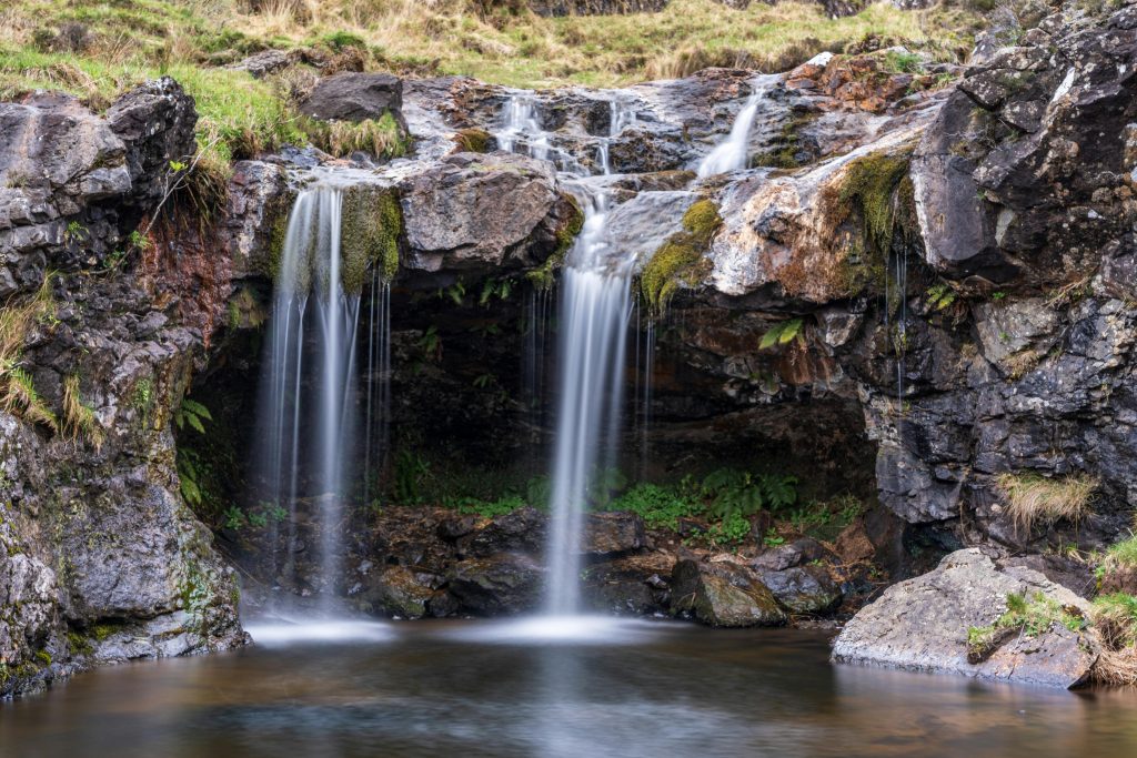 Scenic UK waterfall cascading over rocky ledges into a calm pool - a peaceful spot perfect for family adventures